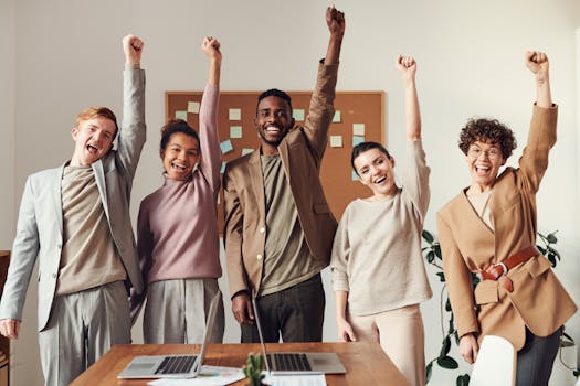 The Power of a Positive Mindset: Transform Your Life with Optimism 4 A diverse team celebrating success with raised hands in a modern office setting.