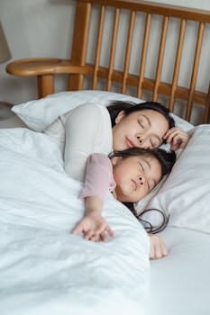 9 Habits of an Immature Wife That Damage Marriage 3 A serene moment capturing a mother and daughter cuddling in bed, enjoying restful sleep.