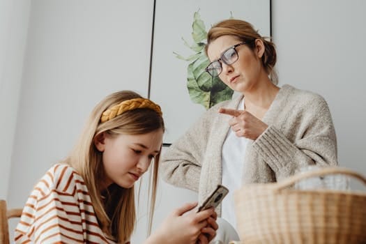 Modern Parenting Challenges And Solutions 4 A mother scolds her teenage daughter for excessive phone use at home.