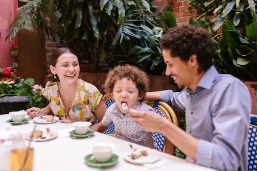 Parenthood Reshapes Married Life: Why Having Kids Strengthens Your Relationship? 5 Happy family sharing dessert together at an outdoor cafe with lush greenery.
