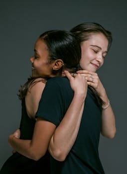 Living with Values That Outlast You: What Will People Remember You For? 7 Two women of different ethnicities share a warm hug, symbolizing love and friendship against a gray backdrop.
