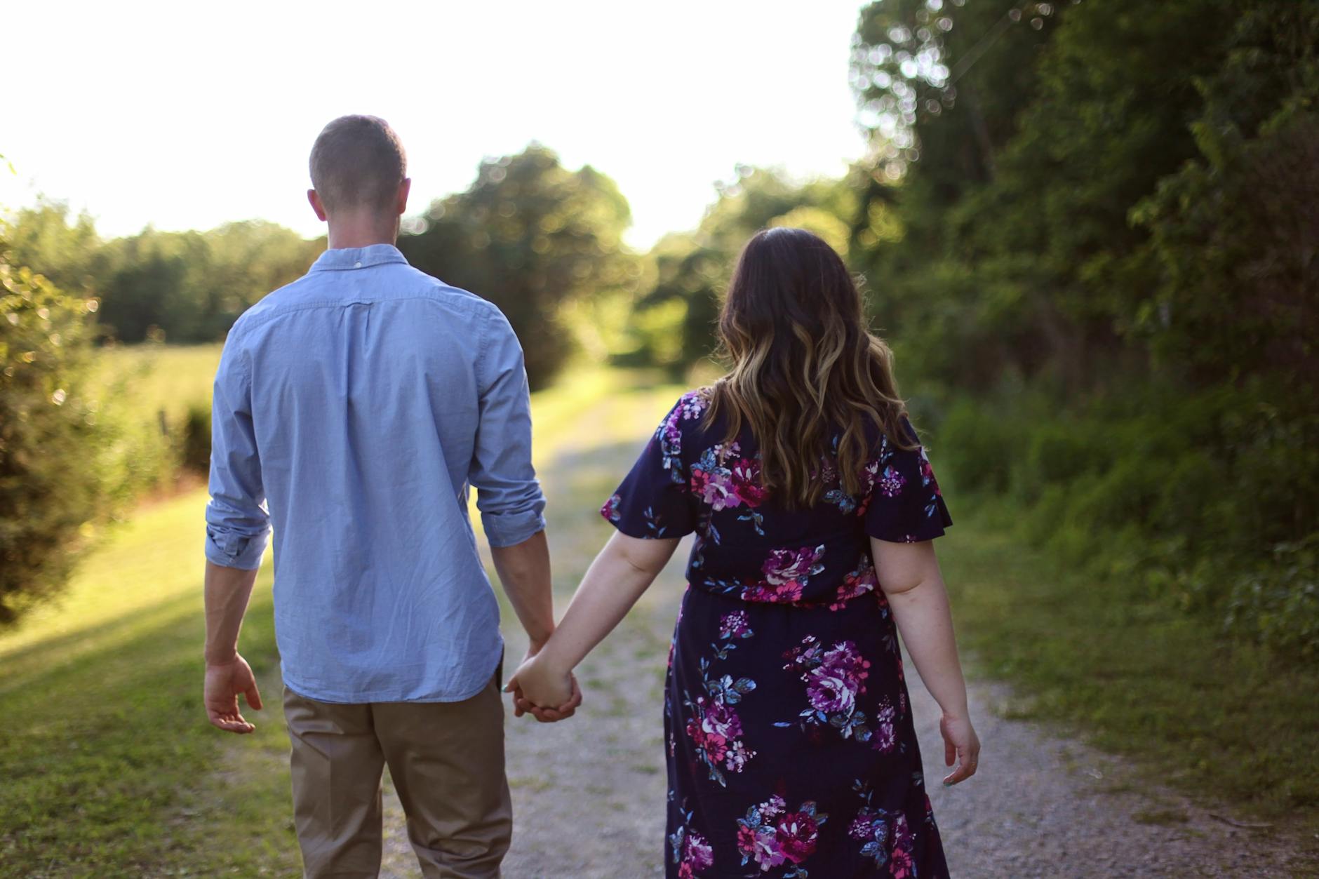 couple holding hands while walking on path