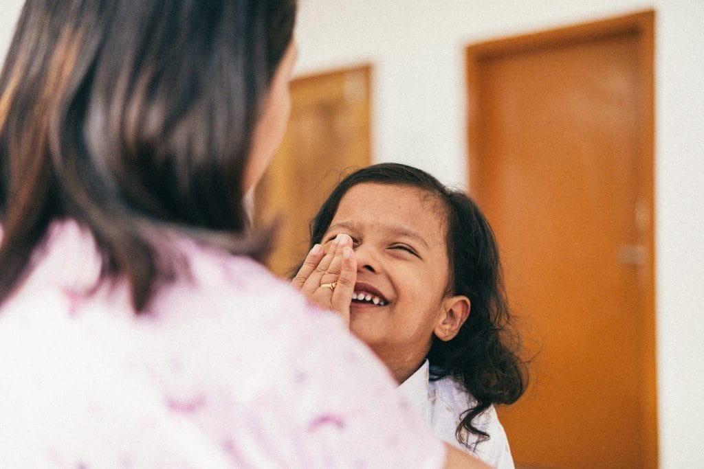 Gentle Parenting Techniques for Indian Parents | Positive Parenting India 3 A loving interaction between mother and daughter, capturing laughter and affection indoors.