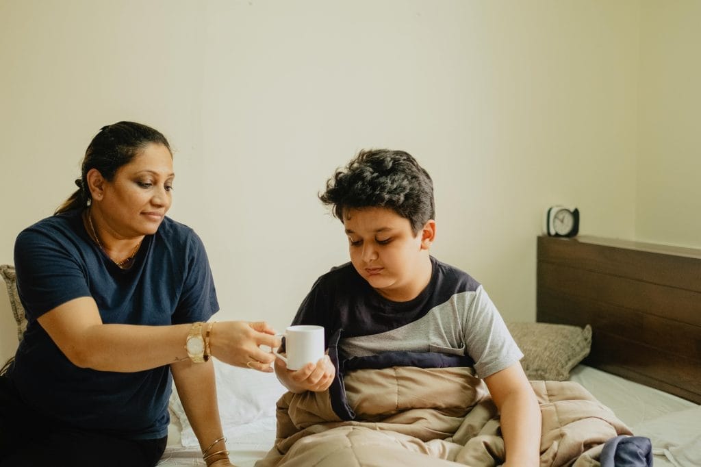 Gentle Parenting Techniques for Indian Parents | Positive Parenting India 4 A nurturing mother hands her son a cup in a cozy morning setting.