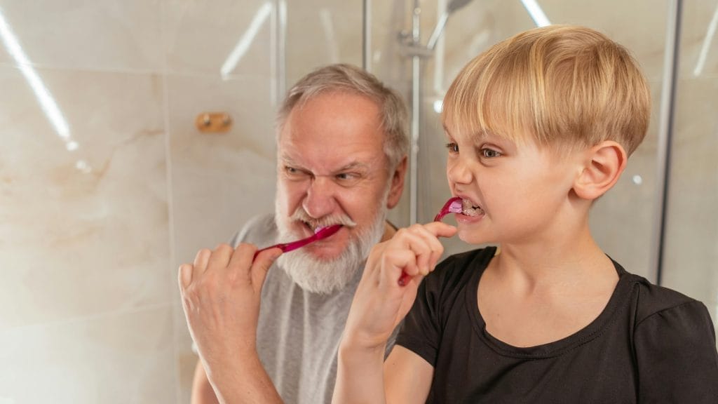 Essential Life Skills to Teach Kids: Building Confidence and Independence from Toddler to Teen 4 Grandfather and grandson brushing teeth, promoting family bonding and oral hygiene habits.