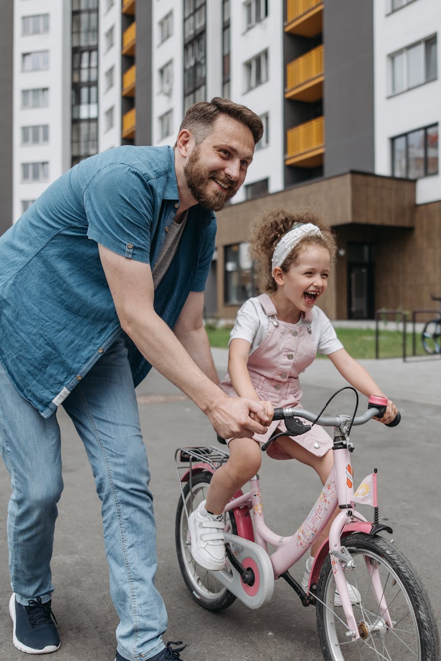 man pushing girl on a bicycle