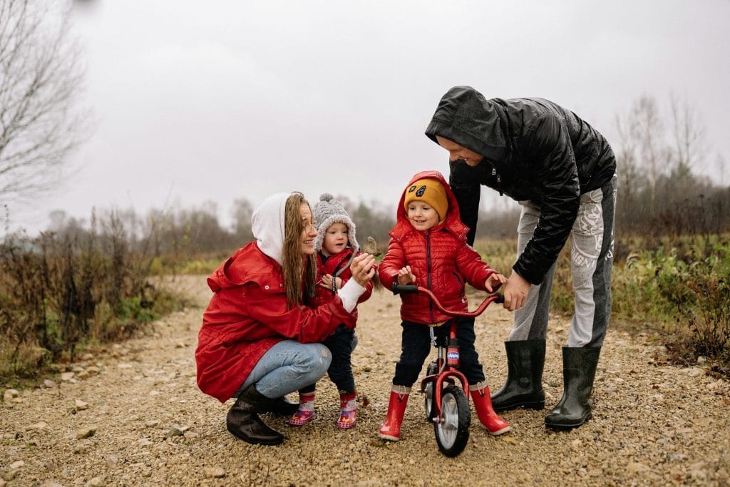 Effective Communication in Parenting: How to Build Stronger Connections 4 Happy family outdoors with children on a dirt path. Parents supporting kids on a bike ride.