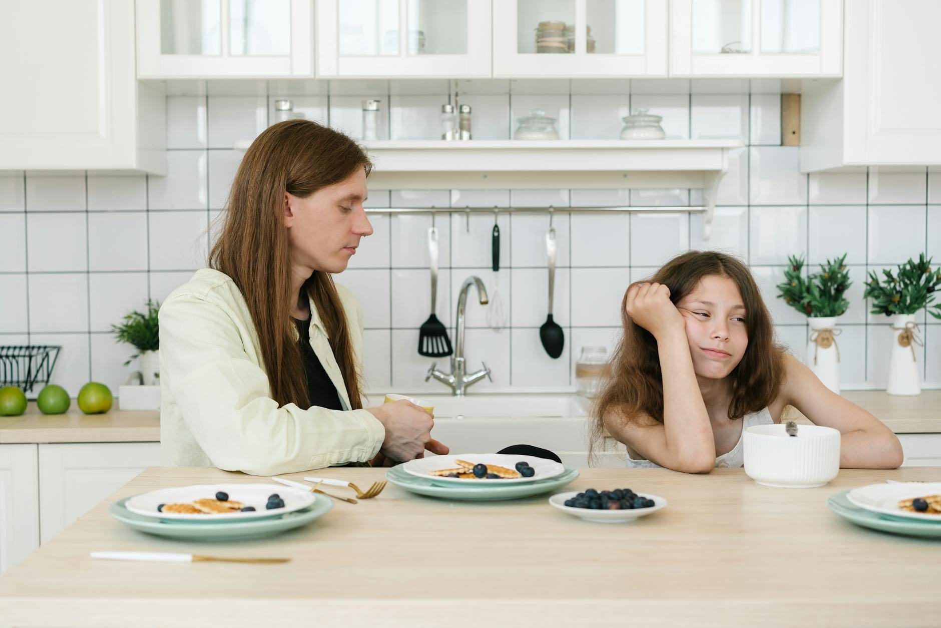 a young girl frowning while sitting beside his father
