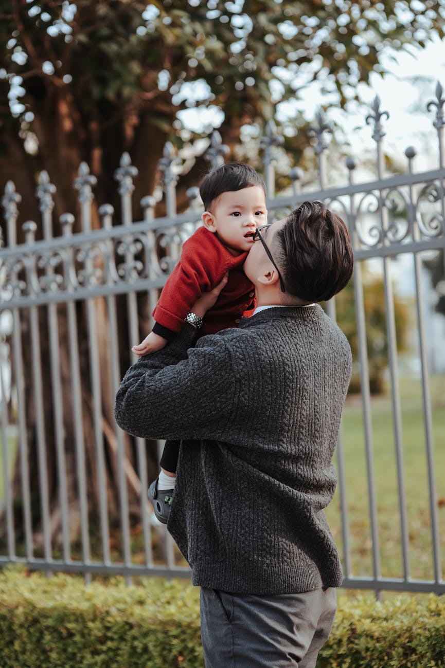 father holding baby outdoors by iron fence