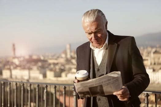 Healthy Morning Routine for Seniors | Science-Backed Habits That Add Strength, Energy, and Long Life 4 Senior man enjoys coffee while reading a newspaper with a cityscape view.