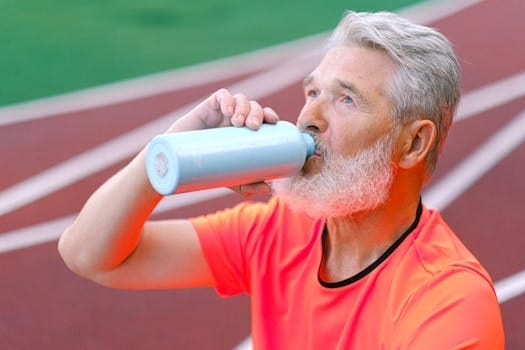 Healthy Morning Routine for Seniors | Science-Backed Habits That Add Strength, Energy, and Long Life 3 Elderly male with gray beard drinking liquid from thermos while resting after training on blurred background of racetrack