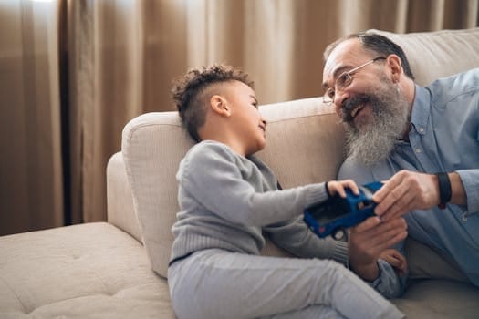 Raising Emotionally Healthy Children Is Our Second Chance as Parents 4 A joyful grandfather and grandson sharing a playful moment on the couch, indoors.