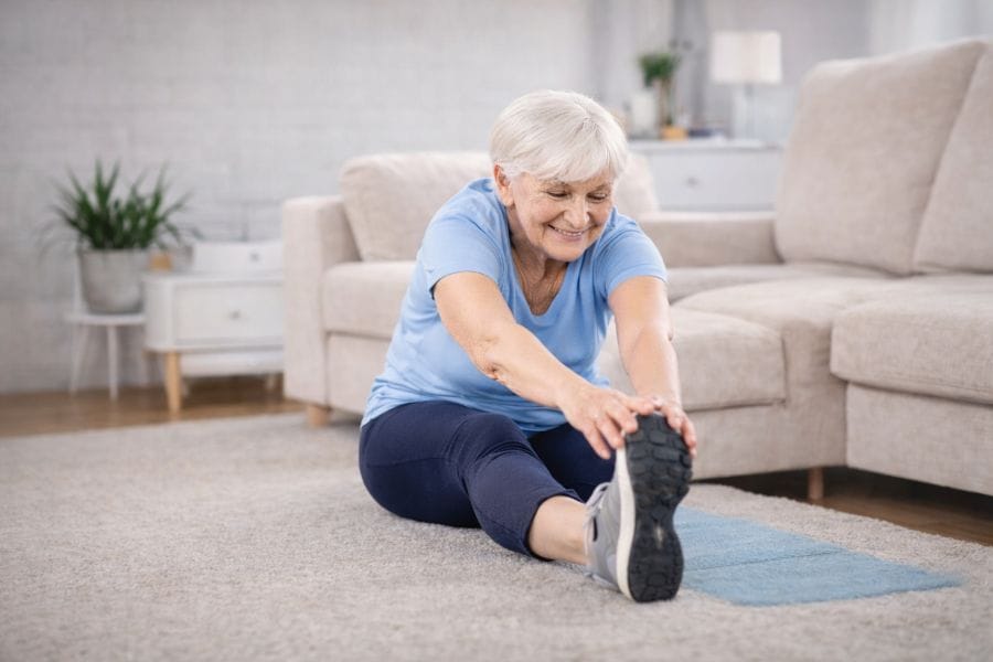Stretching Exercises for Seniors 6 Senior woman performing seated hamstring stretch exercise to improve flexibility