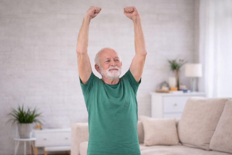 Stretching Exercises for Seniors 4 Senior man doing upper body stretch exercise to improve shoulder flexibility